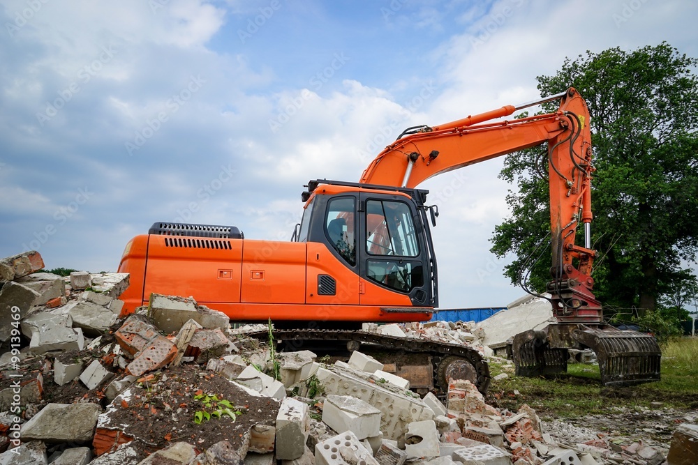 Baubranche - Bagger hinter einer Schutthalde Baubranche - Bagger hinter einer Schutthalde