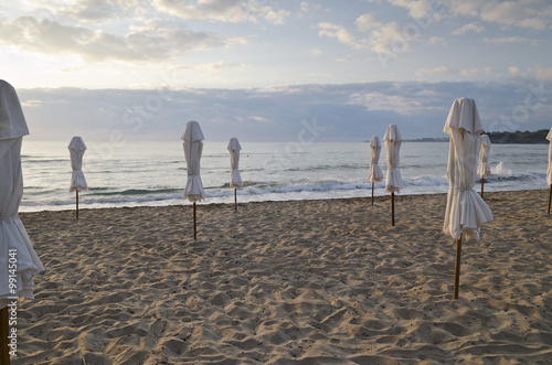 Beach umbrella on deserted coast sea at sunrise photo