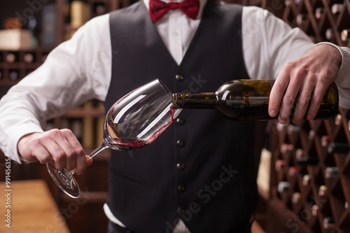 Photo Cheerful male waiter is serving alcohol drink