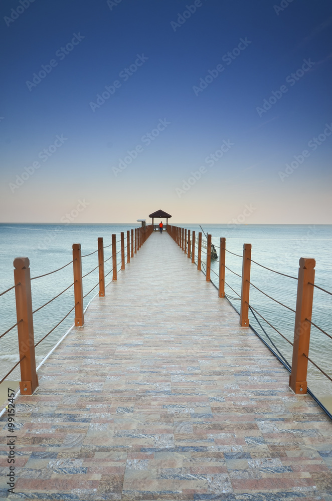 Fototapeta premium long pier heading to the sea under the beautiful blue sky.