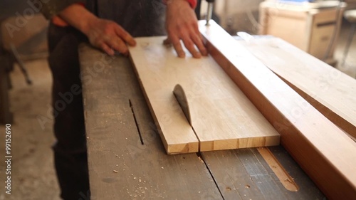 Carpenter sawing plank on a saw circulation in worksho photo