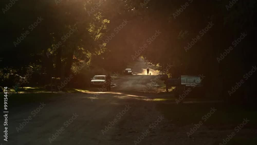 Sun setting over a dirt road in the Mid West, USA. Lens flares through locked-off shot. People walking in the distance. Originally recorded in 4K, UHD. Sun setting over a dirt road in the Mid West, USA. Lens flares through locked-off shot. People walking in the distance. Originally recorded in 4K, UHD.