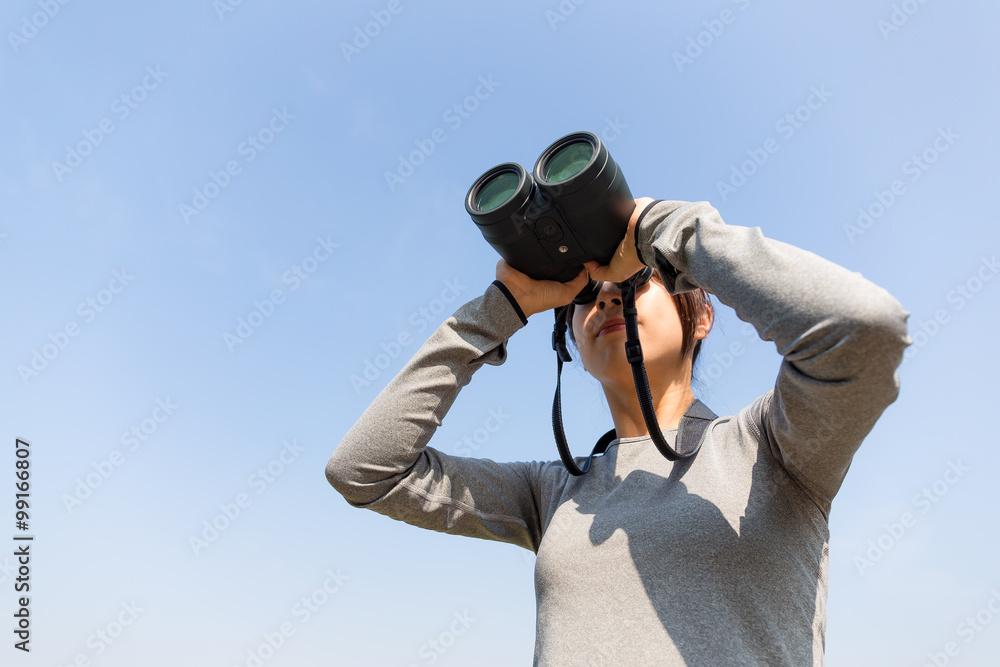 Asian woman looking though binoculars with clear blue sky Asian woman looking though binoculars with clear blue sky