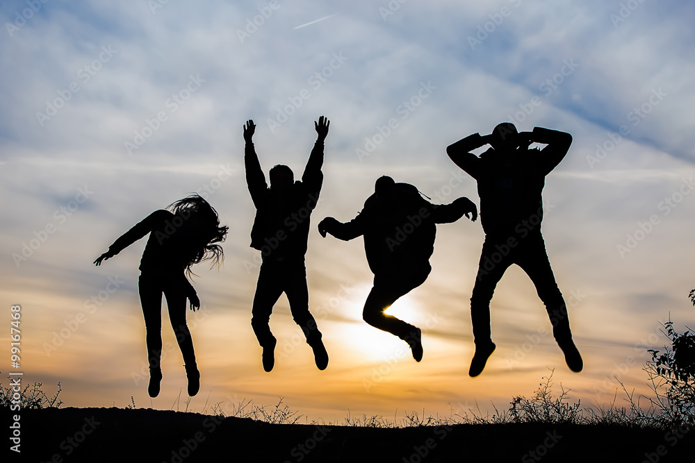 silhouette of a group of four happy people jumping at sunset, happy