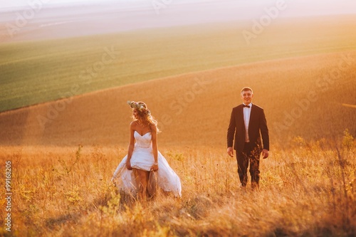 Young newly married couple chasing each other in field