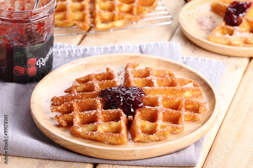 waffles with raspberry jelly on wooden background.