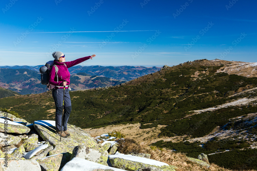 Obraz premium Female Hiker standing on snowy Rocks admiring scenic Winter Mountain View