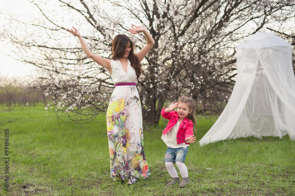 Naklejka premium Mom and daughter dancing in nature together, the family, motherhood, entertainment, recreation, game
