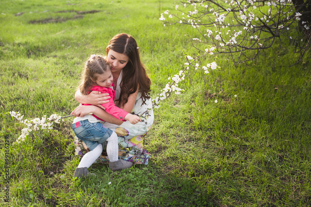 Fototapeta premium Mom kisses and hugs daughter on nature, family, motherhood, child