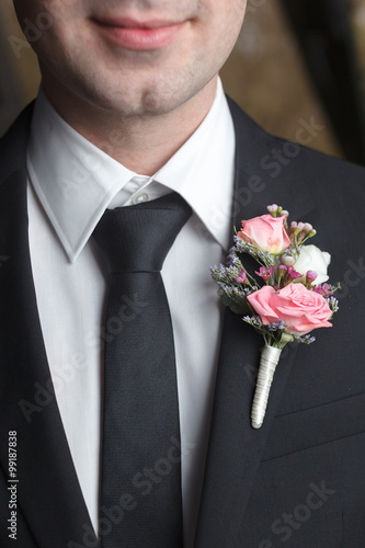 Pink boutonniere on black suit of the groom