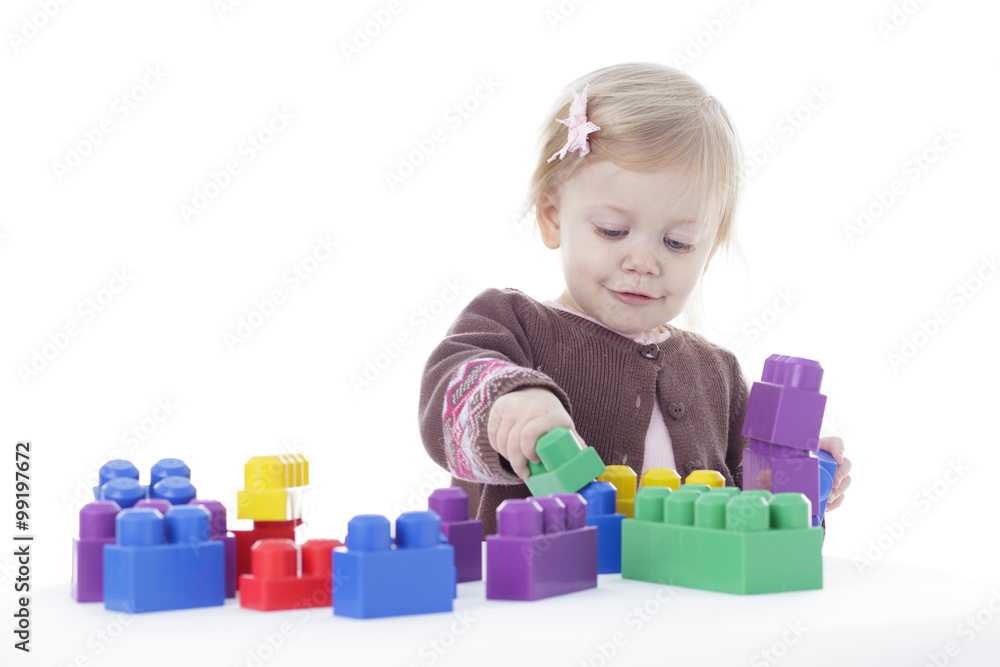 toddler girl playing with colored building blocks, holding in hands, isolated on white background toddler girl playing with colored building blocks, holding in hands, isolated on white background