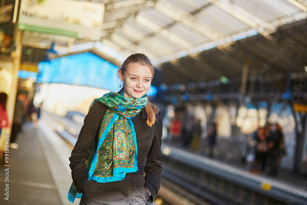 Fototapeta premium Young woman waiting for a train on the platform of Parisian underground