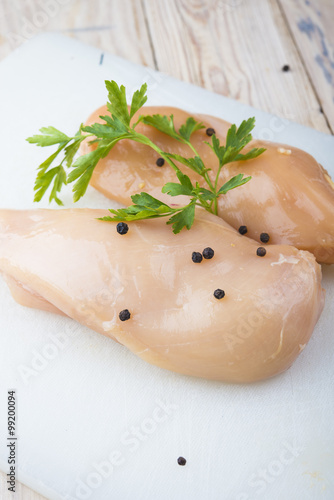 Raw chicken breasts and spices on plastic cutting board