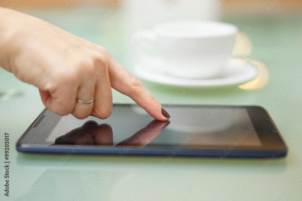 Closeup of woman using tablet computer at home with cup of coff Closeup of woman using tablet computer at home with cup of coff