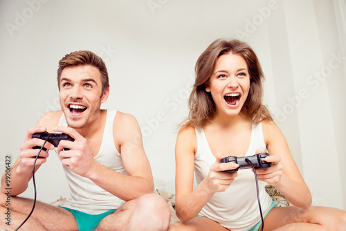 Young couple in love at home playing games joysticks and laughin photo