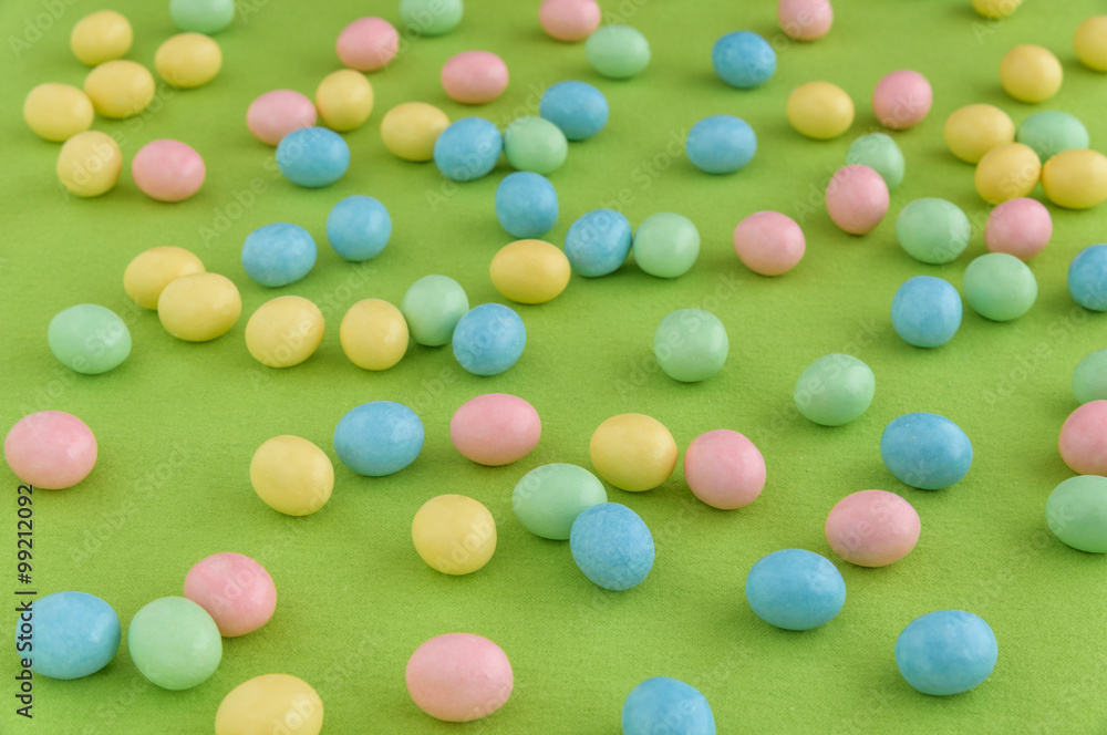 Pastel candy coated Easter eggs spilled out on a spring green background
Pastel candy coated Easter eggs spilled out on a spring green background