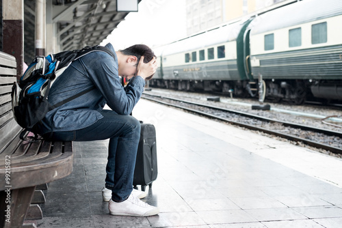 Asian depressed traveler waiting at train station after mistakes
