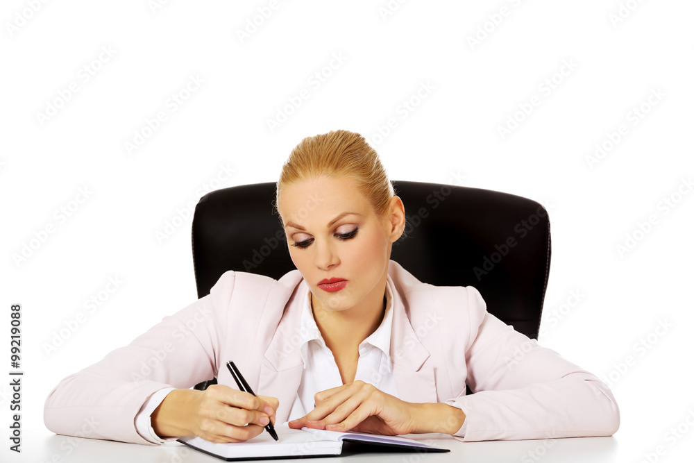 Pensive business woman taking notes behind the desk Pensive business woman taking notes behind the desk