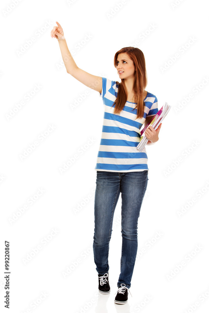 Teenage happy woman holding textbooks and pointing for something Teenage happy woman holding textbooks and pointing for something