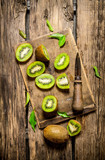 Sliced kiwi on the old board with leaves .