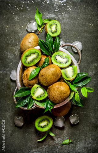 Fresh kiwi with leaves and ice in a pan.
