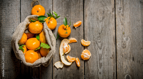 Fragrant tangerines in an old bag with a knife and peeled tangerines.