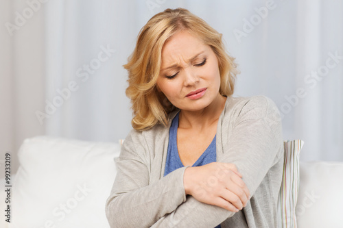unhappy woman suffering from pain in hand at home