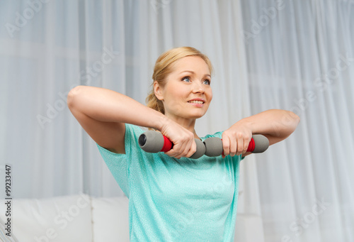 woman exercising with dumbbells on mat at home