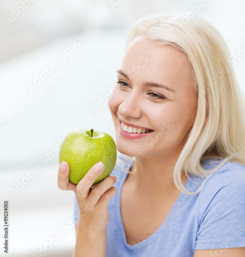 happy woman eating green apple at home