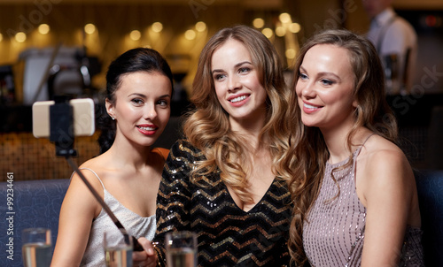 women with smartphone taking selfie at night club