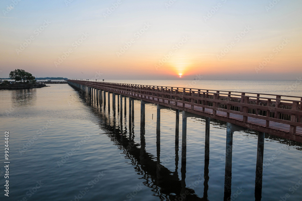 The wooden bridge in the sea with sunrise in the morning