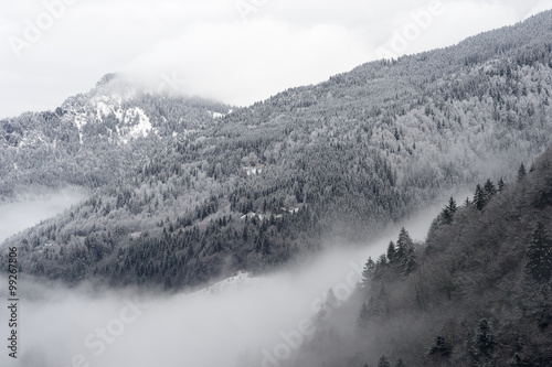 Mountain valley with snow and low clouds.
