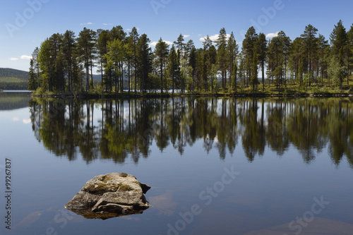 Swedish lake with reflection and rock in foreground.
