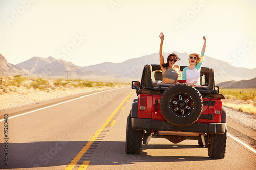 Friends On Road Trip Driving In Convertible Car photo