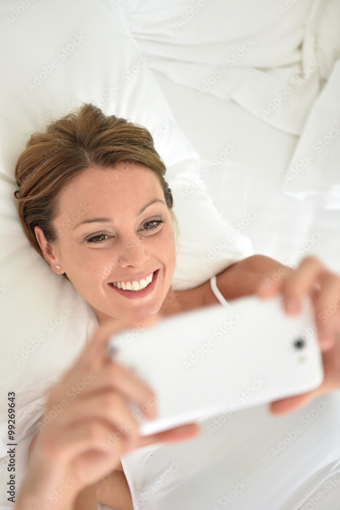 Woman laying on bed and using smartphone Woman laying on bed and using smartphone