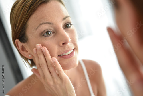 Woman applying facial cream on her face photo