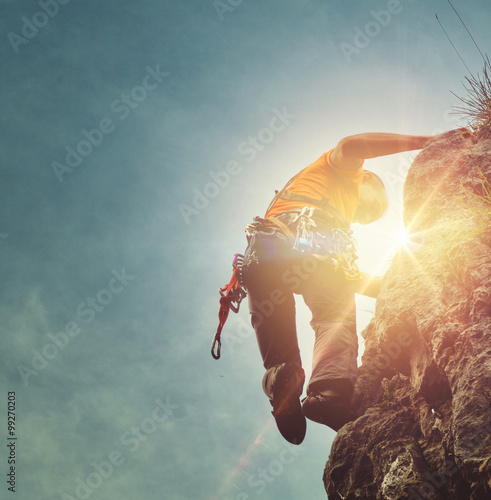 Man mountain climbing with a sunburst
