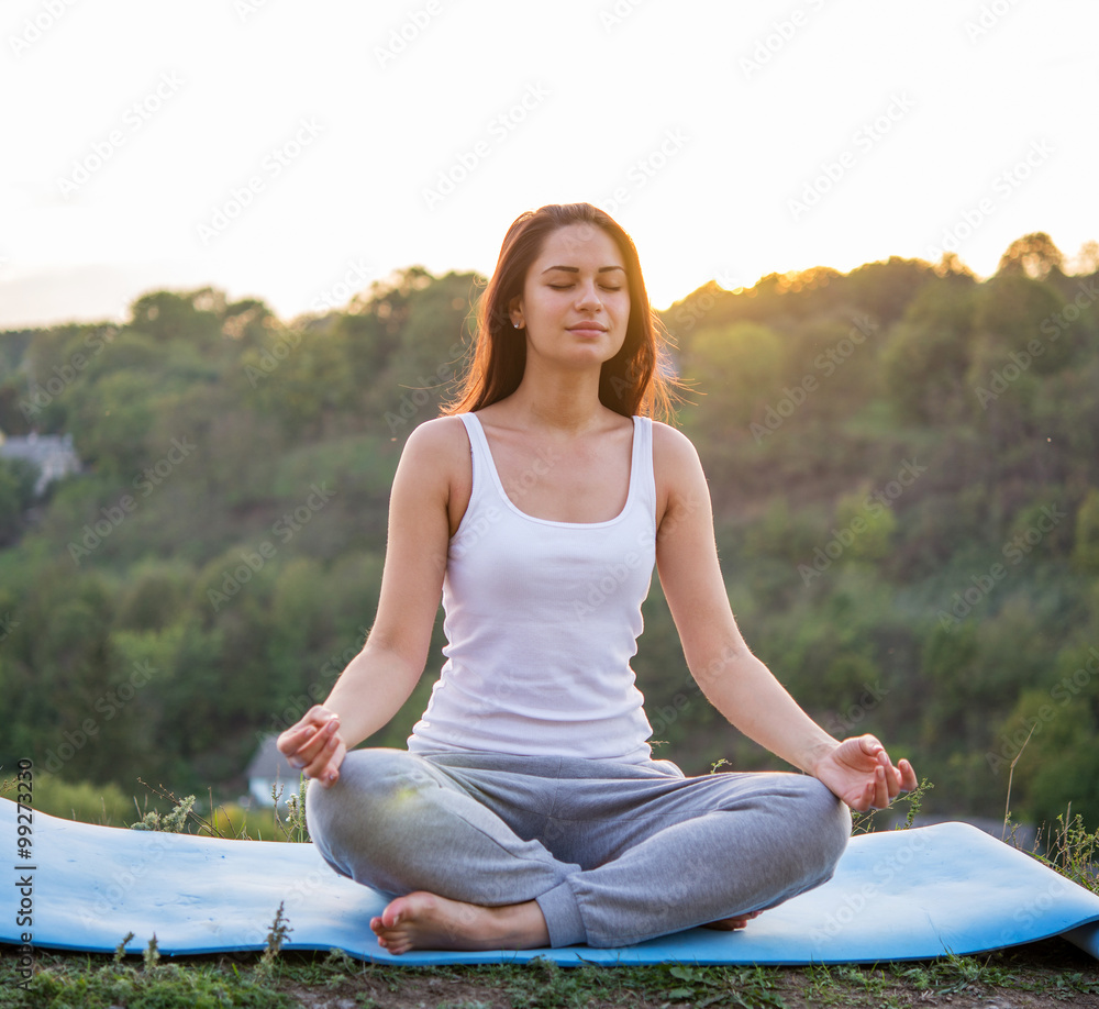 beautiful girl meditating at sunset