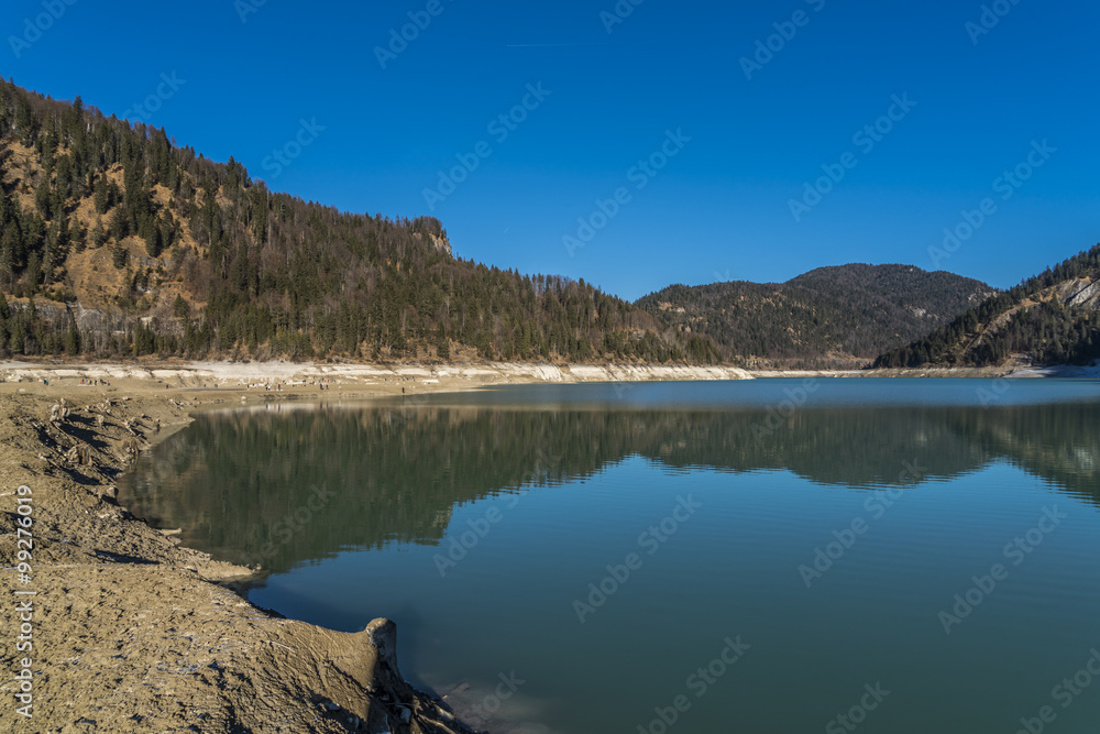Abgelassener Sylvensteinspeicher unter blauem Himmel und blauem Restwasser Abgelassener Sylvensteinspeicher unter blauem Himmel und blauem Restwasser