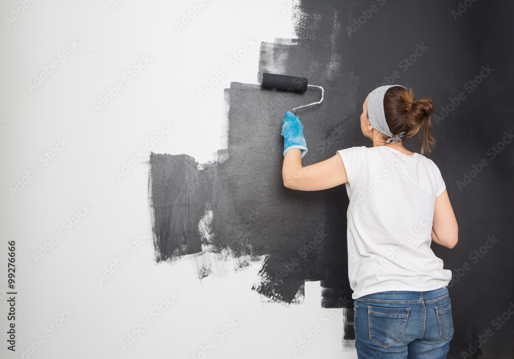 Woman paint wall at home.