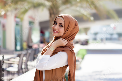 Smiling girl in hijab covering her eyes with happiness in Dubai Marina