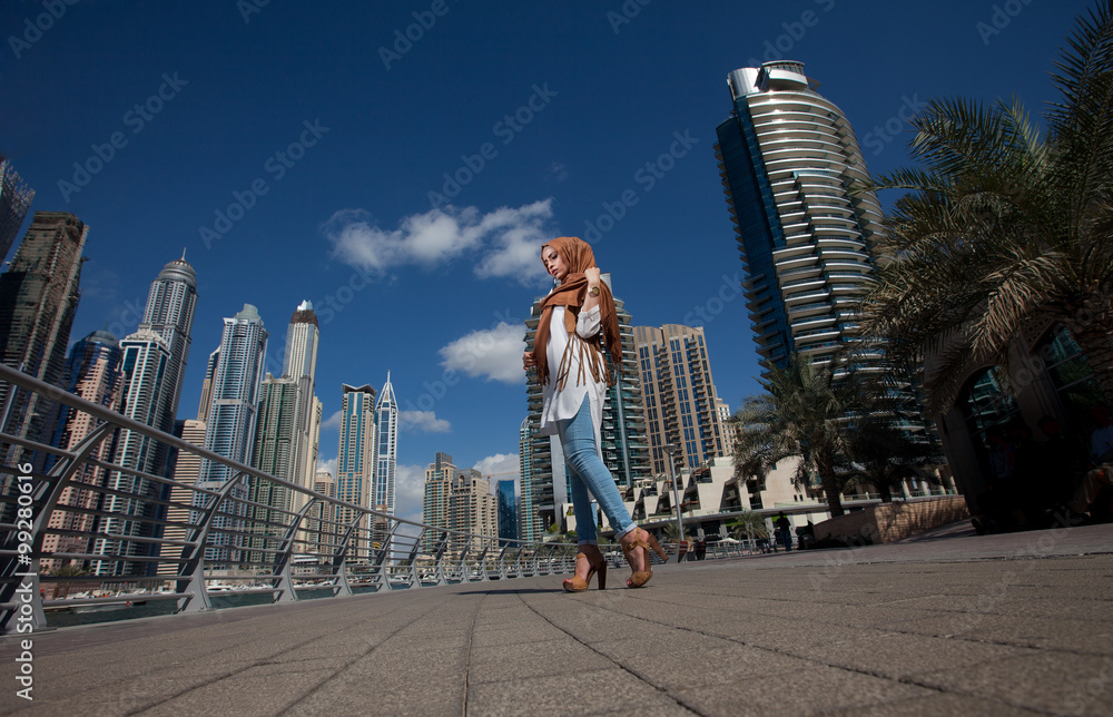 Smiling girl in hijab covering her eyes with happiness in Dubai Marina