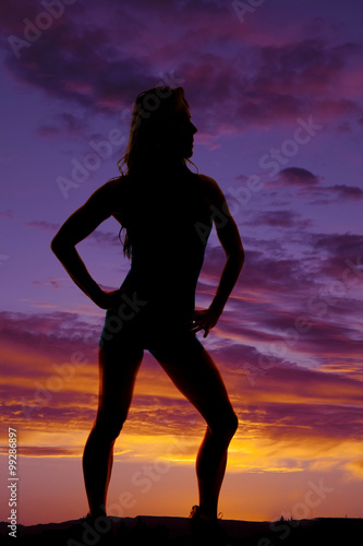 silhouette of woman standing hands on hips in sunset
