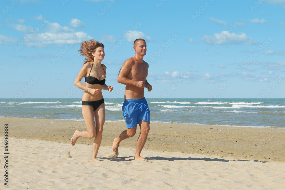young couple jogging on beach doing fitness on holiday - attractive girl and boy running on the seashore on a sunny day young couple jogging on beach doing fitness on holiday - attractive girl and boy running on the seashore on a sunny day