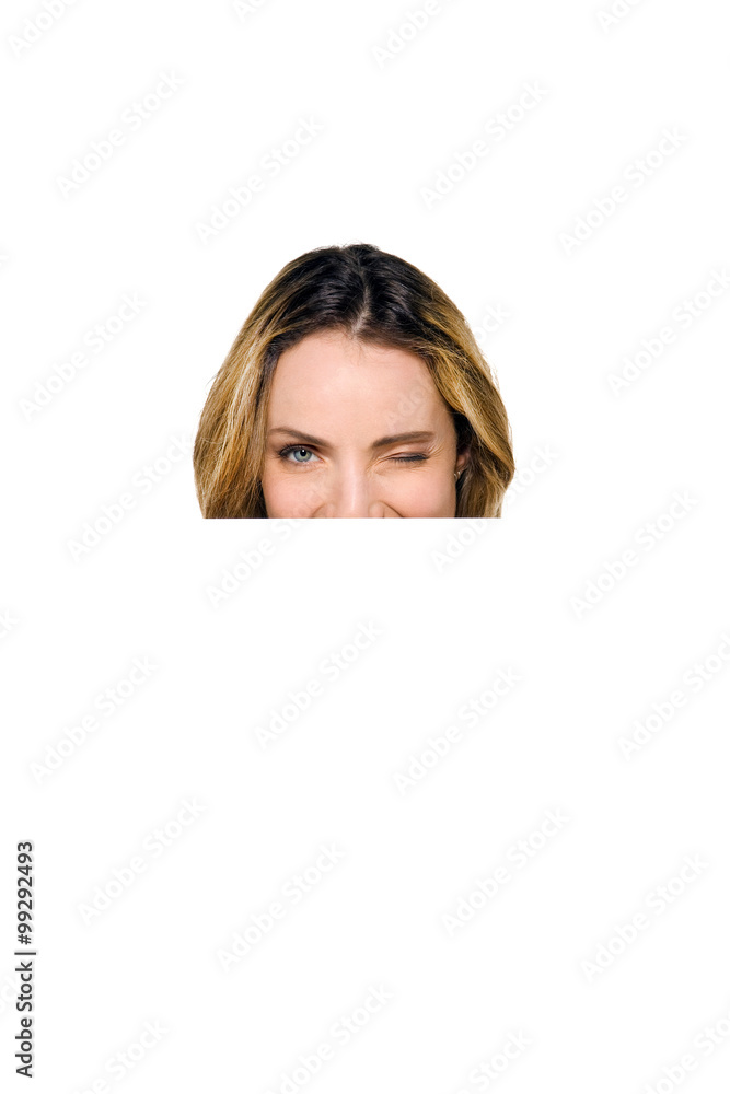 Behind a white board - Woman hiding or peeking behind a white sign Behind a white board - Woman hiding or peeking behind a white sign