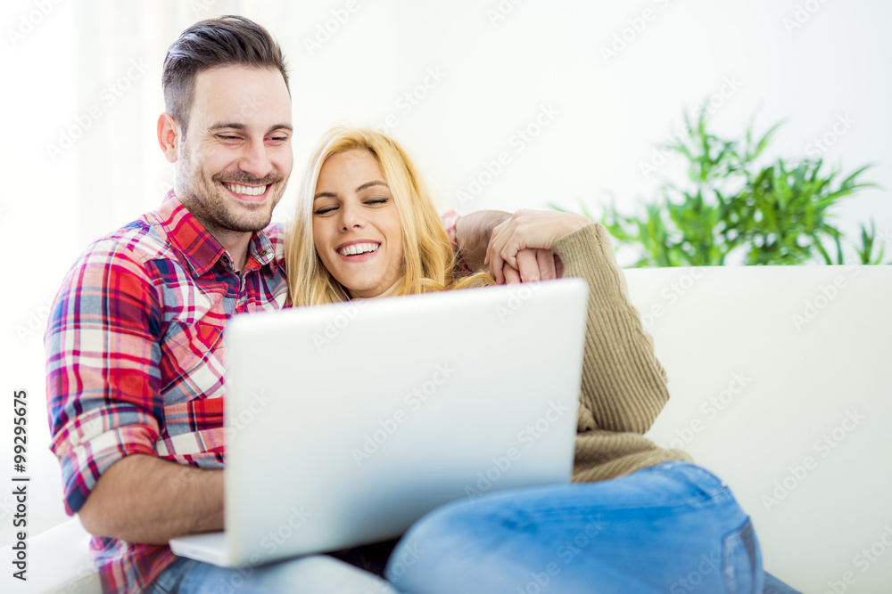 Young couple browsing internet at home, using laptop and smiling