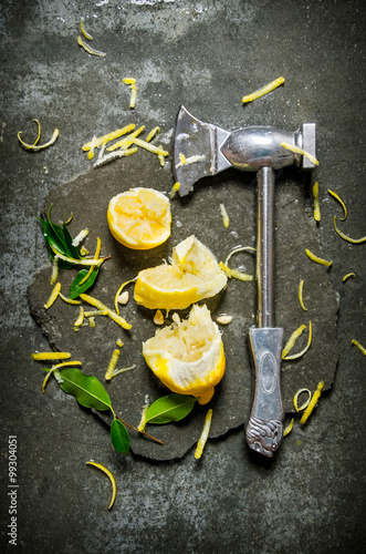 Axe with lemon and leaves on a stone stand.
