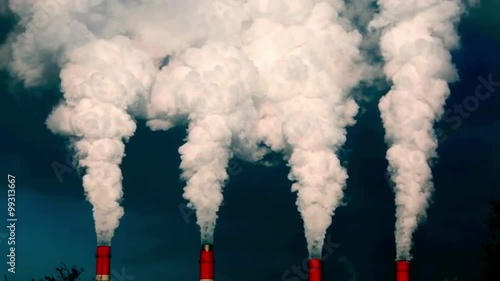 Dramatic view of smoke or steam columns from four red stacks on dark blue background. Dioxide carbon and warm, exhausting with the industry chimneys in the atmosphere, is the great danger for ecology.