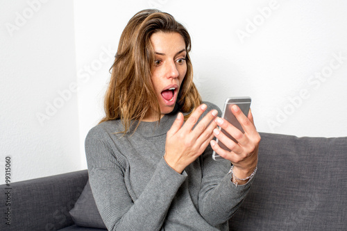 Woman suprised while looking on smartphone