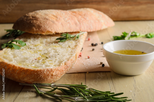 Sliced bread ciabatta watered with extra virgin olive oil with herbs  on wooden background